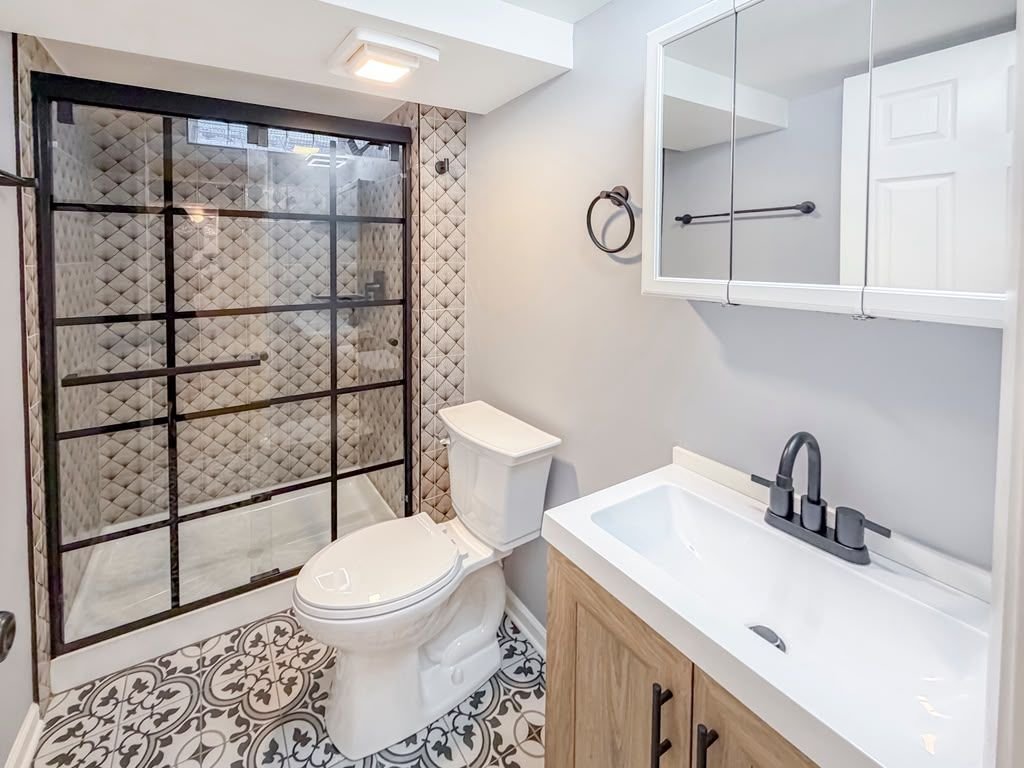 Baño terminado con regadera de vidrio y marco negro