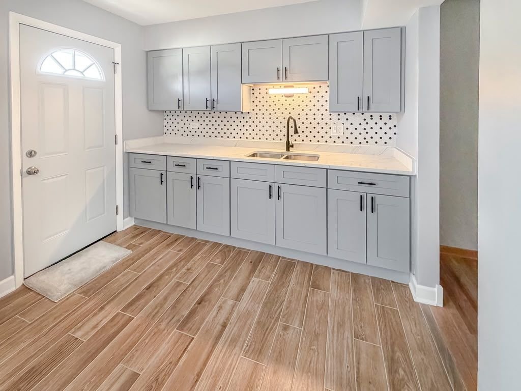 Finished kitchen with gray shaker cabinets, quartz counters and tile backsplash