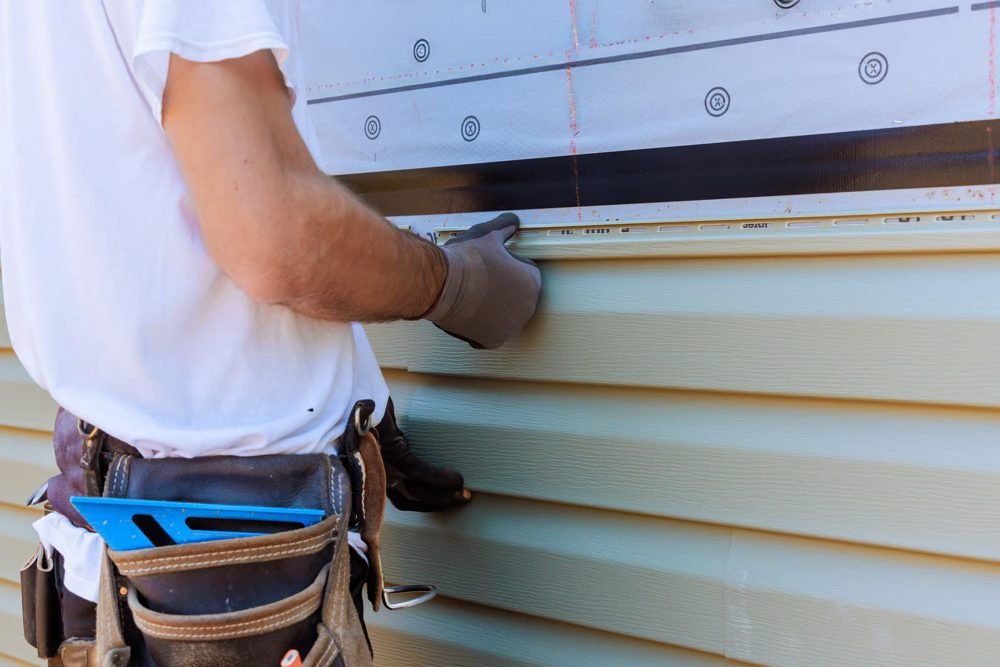 Instalación de revestimiento de vinilo en un muro exterior (foto de stock)